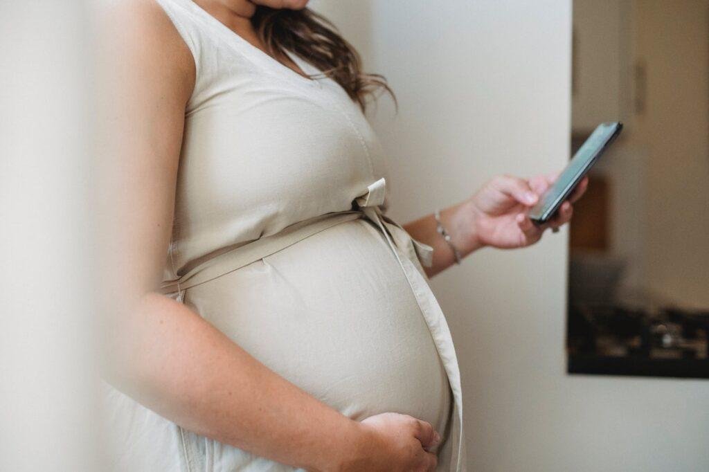 anonymous pregnant female checking notification on cellphone
